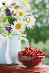 A bouquet of wildflowers and a glass bowl of red currant