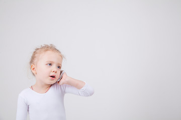 Portrait of the little girl's positive that talking on a cell phone, isolated on white background.