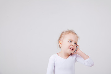 Portrait of the little girl's positive that talking on a cell phone, isolated on white background.