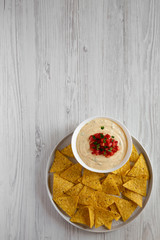 Homemade cheesy dip in a bowl, yellow tortilla chips, top view. Overhead, from above, flat lay. Copy space.