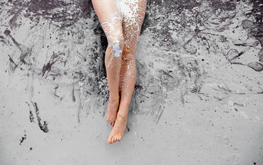 beautiful woman legs with white paint splashed on the gray painted studio floor