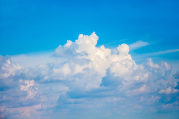 Naklejka na ściany i meble A white curly cumulonimbus cloud on the background of a blue sky_