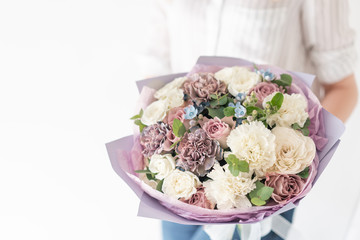 Beautiful bouquet of mixed flowers in woman hand. the work of the florist at a flower shop. Delicate Pastel color. Fresh cut flower. White and lilac color