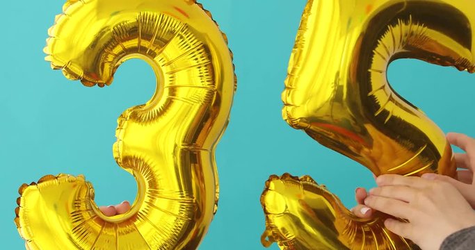 Gold foil number 35 celebration balloon on a blue background
