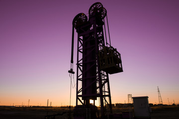 Oil pumps are running in the sunset at the oil field.