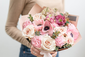 Beautiful bouquet of mixed flowers in woman hand. the work of the florist at a flower shop. Delicate Pastel color. Fresh cut flower. Pink and white color