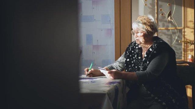 An elderly woman with a credit card examines payment documents. Social inequality