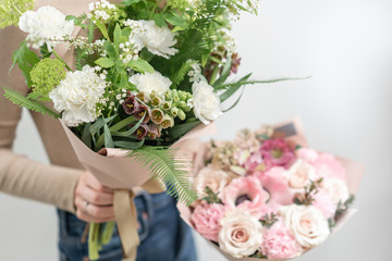 Two Beautiful bouquets of mixed flowers in womans hands. the work of the florist at a flower shop. Delicate Pastel color. Fresh cut flower. Green and pink color