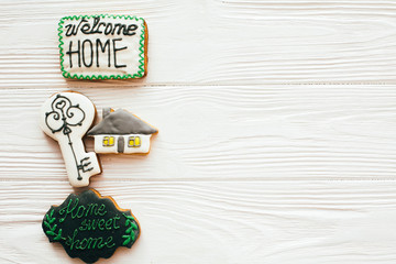 Moving in new house, Welcome home set. Key, house, welcome sign cookies on white wood, flat lay with space for text. Dream home concept. Home Sweet Home.
