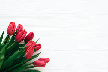 Happy Mothers day. Beautiful red tulips on white wooden background flat lay. Pink tulips border on...