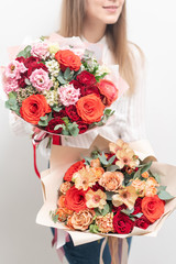two Beautiful bouquets of mixed flowers in womans hands. the work of the florist at a flower shop. Delicate Pastel color. Fresh cut flower. Red and peach color