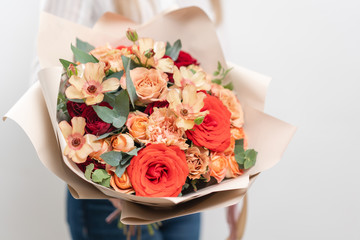 Beautiful bouquet of mixed flowers in womans hands. the work of the florist at a flower shop. Delicate Pastel color. Fresh cut flower. Red and peach color