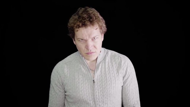 Furious man raging in slow motion. This guy is so angry he's making an evil screaming rage face. Raging and livid, man moves in close with serious expression.