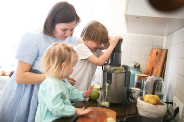 Mother and children cut apples and squeeze juice
