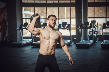 Fototapeta na wymiar athletic young man with beard doing lifting weight at the gym opposite the camera. exercise on the shoulders with weight dumbbells. Guide how to do lifts for shoulders