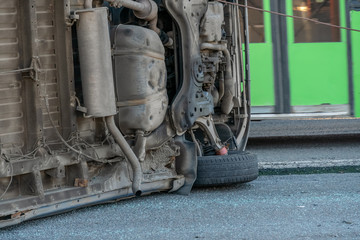 Fototapeta premium Upside down car minibus after an accident lies on its side on the road, the bottom of the car looks at the camera. Bottom inverted car minibus close-up
