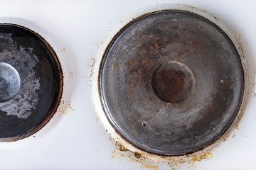 Contaminated white old electric stove with soot around the electric hot plates close up