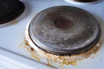 Contaminated white old electric stove with soot around the electric hot plates close up