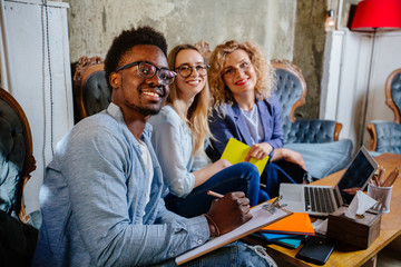 Team of black man and two blond women freelancer meeting for working solution in modern home office interior. Joint project real people models concept.
