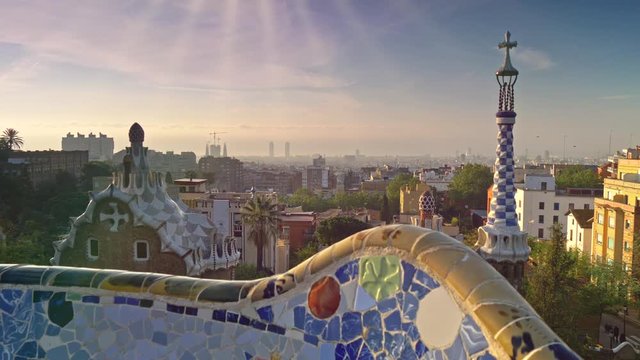 Crane shot of Barcelona city view from Guell Park. Sunrise view of colorful mosaic building in Park Guell. UHD, 4K