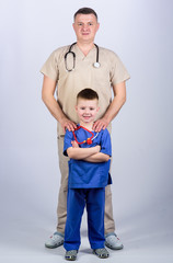 little boy with dad in hospital. father and son in medical uniform. happy child with father with stethoscope. family doctor. medicine and health. Another working day. hospital team of doctors