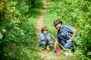 Farm family. Little boy and father in nature background. Gardening tools. Spring gardening routine. Planting flowers. Gardening hobby. Dad teaching little son care plants. Little helper in garden