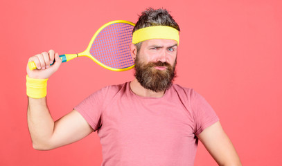 Tennis sport and entertainment. Man bearded hipster wear sport outfit. Concentrate on goal. Sport achievement. Athlete hipster hold tennis racket in hand red background. Tennis player vintage fashion