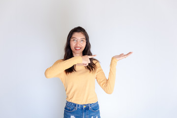 Photo of happy young woman standing on isolated white background. Looking camera showing copyspace pointing.