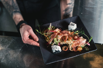 Fresh salad with prosciutto, tomato, lettuce and blue cheese on a stone plate