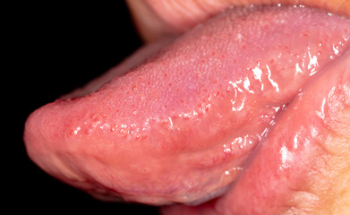 Tongue in the mouth of a man on a black background.