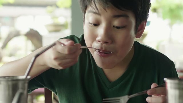 Young asian boy eating fried rice with meat for breakfast.