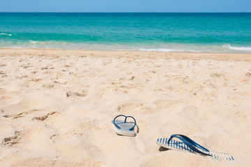 Summer vacation concept. Slippers on tropical beach. Sandy beach with sea and blue sky background. Summer, holiday -Image