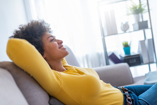 Happy Woman Relaxing On Comfortable Soft Sofa Enjoying Stress Free Weekend At Home, Calm Satisfied Girl Stretching On Couch Thinking Of Pleasant Lazy Day, Dreaming And Planning Sunday Morning