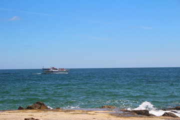 The beautiful sea floats a white yacht along the rocky shore. Beautiful Wallpapers for your computer.