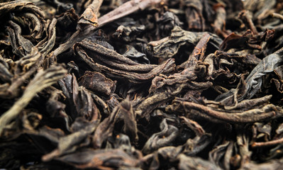 Fototapeta premium Macro shot of a high quality black tea. Black tea background close up. Leaf closeup. Background of dried tea leaves of dark color. Macro photo. Pile of black tea leaves.