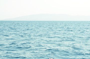 Obraz premium Sea water surface and waves stretch out to the horizon where islands are visible far away.