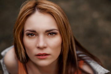 Dramatic Portrait of a girl with red long hair, looking into the camera with big eyes.