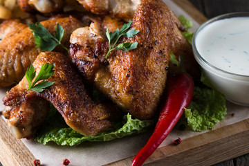Close-up photo of bbq chicken wings with fries and beer. Barbeques meat with sauces, ketchup, mayonnaise. Fast and junk food concept. 