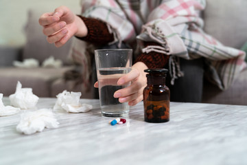 hand holding water glass with pills on table