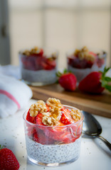 Chia pudding with strawberries walnuts and honey. Blurred background. White and red napkins 