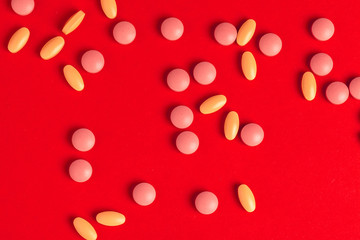 White pills spilling out of a toppled white bottle on red background