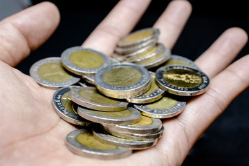 Hand and finger on Thai coins currency with black background. Abstract of saving money account. 