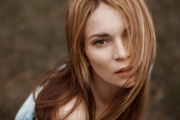 Naklejka premium Dramatic Portrait of a girl with red long hair, looking into the camera with big eyes.