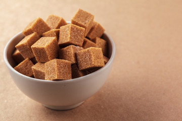 Brown cane sugar cubes on a light brown background