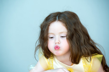 Little girl with long hair blowing bubbles