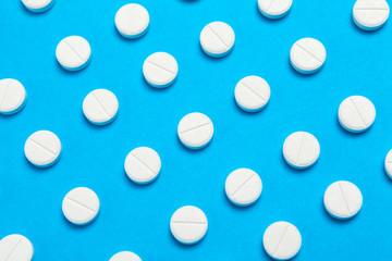 Chaotically scattered white pills on a blue background pattern. White pills background. Texture for design