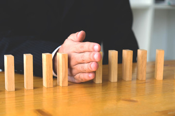 Business hand stops domino continuous overturned meaning that hindered business failure. Stop over this business failure concept.