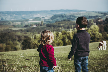 Deux jeunes enfants en train de regarder des vaches dans un champ