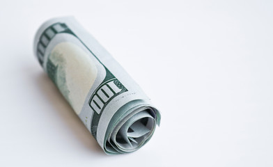 One hundred dollar bills rolled into a tube on a light background