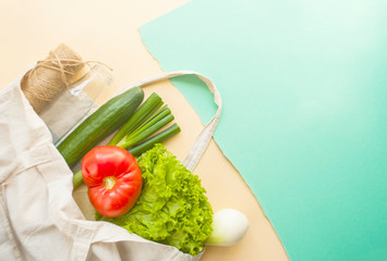 Fresh fruits and vegetables in eco bag on beige and turquoise color background with copyspace. Plastic free concept.